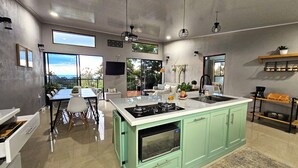 A modern kitchen with a central island, a dining area with a view, and a small seating area.