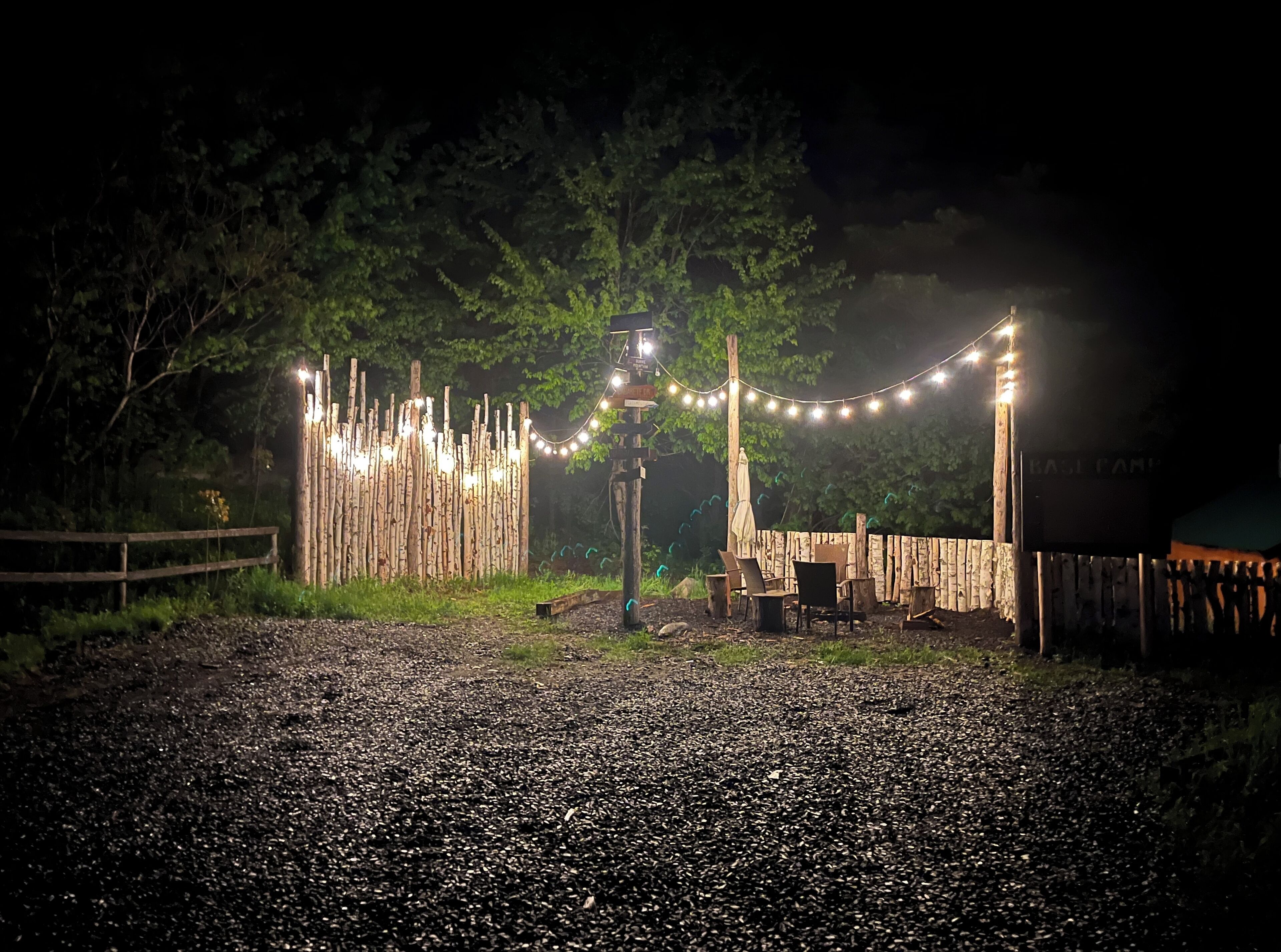 A gravel path leading to a wooden fence with string lights.