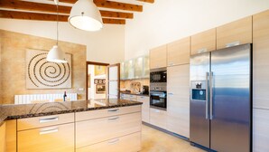 Eine moderne Küche mit Holzschränken, einem Edelstahlkühlschrank und einer Arbeitsplatte aus Granit.