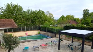 A backyard with a swimming pool, lounge chairs, and a pergola. - Comfortable villa with pool in the countryside (Foissiat)