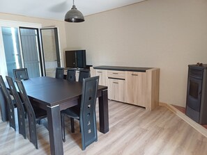 A modern kitchen with a dining table and chairs, a built-in oven, and a TV. - Comfortable villa with a pool in the countryside (Foissiat)