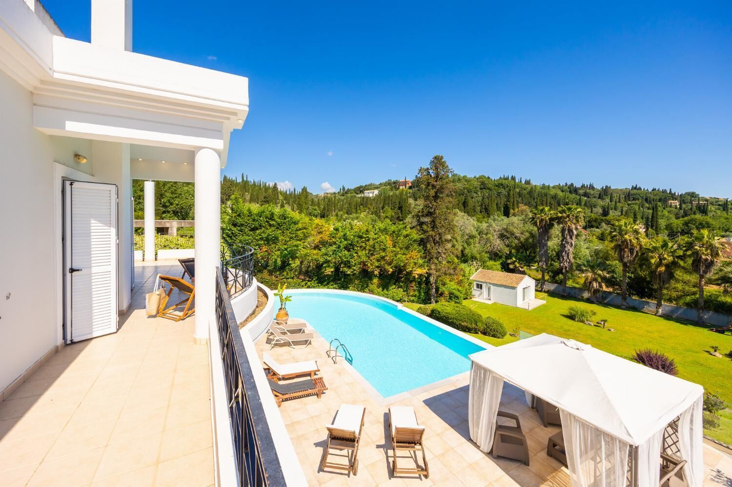 Una villa moderna con piscina privada, mobiliario de exterior y una vista panorámica del campo.