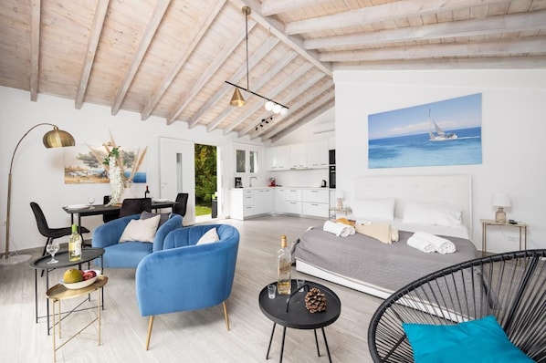 Ein modernes, helles Zimmer mit einem Bett, blauen Stühlen, einem Essbereich und einer Küche.