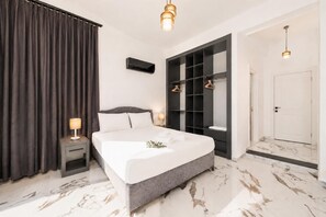 A modern bedroom with a large bed, a built-in wardrobe, a bedside table, and a nightstand.