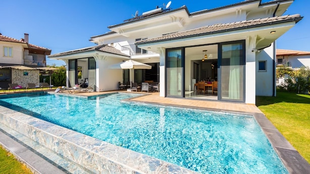 Ein modernes Haus mit Pool, großen Glasfenstern und einem gepflegten Rasen.