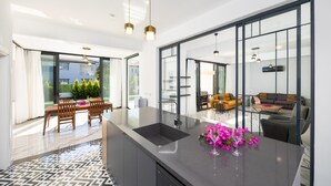 Eine moderne Küche mit einer großen Kochinsel, einem Essbereich mit Tisch und Stühlen sowie einem Wohnbereich mit Sofa und Couchtisch.