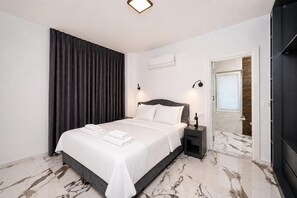 A modern bedroom with a bed, nightstands, a dark curtain, an air conditioning unit, and a view of a wooden door.