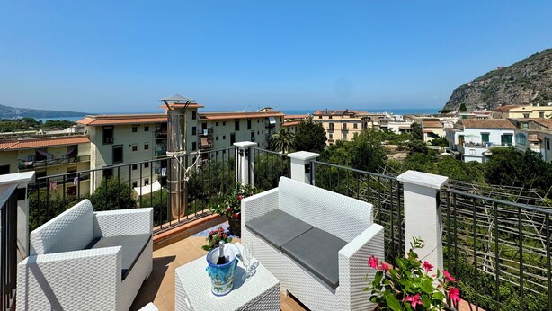 A balcony with wicker furniture, a potted plant, and a bottle of champagne. - YourHome - La Famiglia Apartment (Meta)