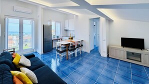A modern apartment with a dining area, kitchen, and living space. - YourHome - La Famiglia Apartment (Meta)