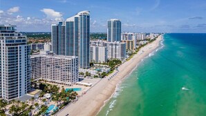 A coastal cityscape with high-rise buildings, a beach, and clear turquoise waters. - 1BD/1.5BTH BeachFront Resort Style. Gym, WiFi, Free Parking, Jacuzzi, GameRoom. (Hollywood)