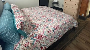 Una camera da letto con un letto, una cassettiera, una televisione e una porta.
