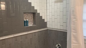Un bagno con vasca, doccia e pareti piastrellate.