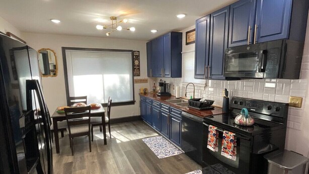 Una cucina moderna con mobili blu scuro, un fornello nero e un microonde.