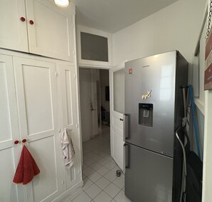 A compact kitchen with white cabinets, a stainless steel refrigerator, and a water dispenser.