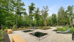 A landscaped outdoor area with a rectangular pool, lounge chairs, and wooden benches. - Tremblant Prestige - Verbier 13-203 (Mont-Tremblant)