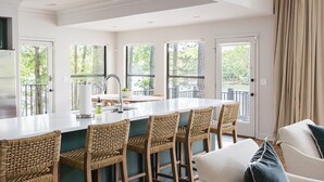 Una cocina moderna con una isla grande, taburetes de bar y vistas al exterior.