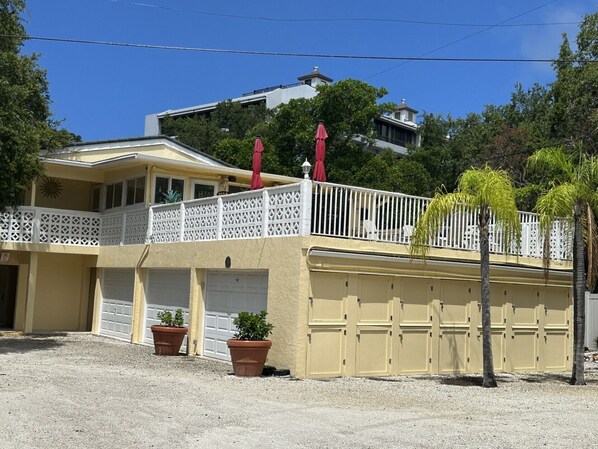 A two-story building with a balcony, potted plants, and a garage. - Siesta Key Access- Large Deck w/ Bay View: 2-Bdrm Condo-sleeps 6 Heated Pool! (Sarasota)