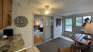 A kitchen with a granite countertop, wooden cabinets, a ceiling fan, and a view of a living area through a glass door. - Siesta Key Access- Large Deck w/ Bay View: 2-Bdrm Condo-sleeps 6 Heated Pool! (Sarasota)