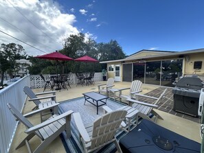An outdoor patio with Adirondack chairs, a grill, and a pool area. - Siesta Key Access- Large Deck w/ Bay View: 2-Bdrm Condo-sleeps 6 Heated Pool! (Sarasota)