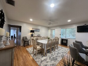 A dining area with a table, chairs, a lamp, and a television. - Siesta Key Access- Large Deck w/ Bay View: 2-Bdrm Condo-sleeps 6 Heated Pool! (Sarasota)