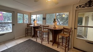 A sunroom with a ceiling fan, a dining table with chairs, and large windows offering a view of the outdoors. - Siesta Key Access- Large Deck w/ Bay View: 2-Bdrm Condo-sleeps 6 Heated Pool! (Sarasota)
