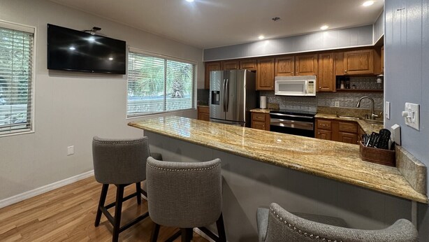 A modern kitchen with granite countertops, stainless steel appliances, and wooden cabinets. - Siesta Key Access- Large Deck w/ Bay View: 2-Bdrm Condo-sleeps 6 Heated Pool! (Sarasota)