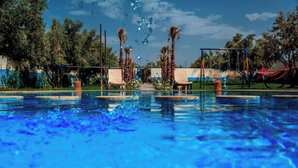 A swimming pool with lounge chairs and palm trees in the background. - Magnifique Villa Riad Marrakech Route Ourika (Marrakesh)