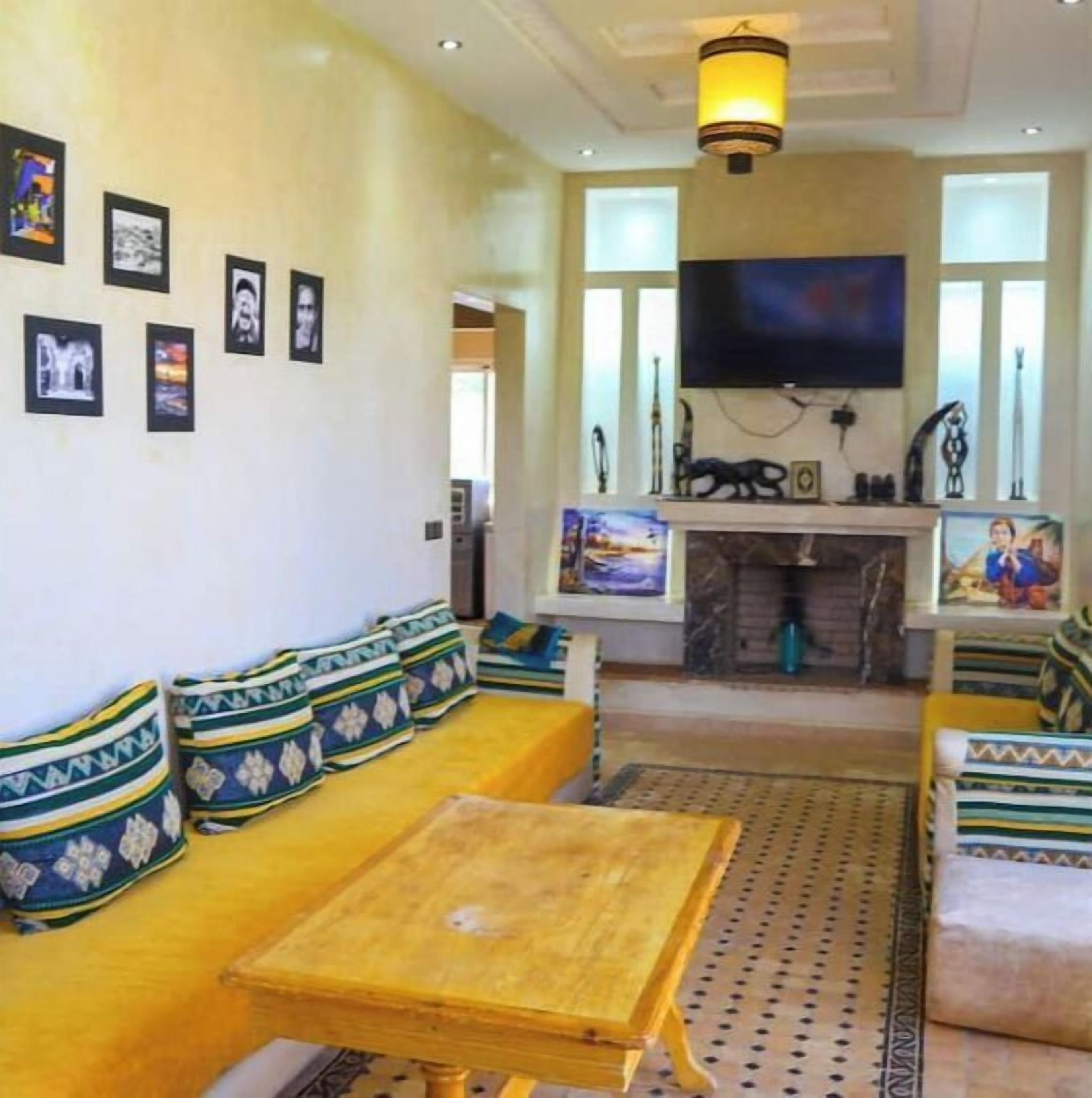 Una sala de estar con un sofá, una mesa de centro y un televisor de pantalla plana montado en la pared.