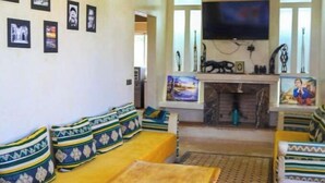 A living room with a sofa set, a coffee table, and a flat-screen TV mounted on the wall. - Magnifique Villa Riad Marrakech Route Ourika (Marrakesh)