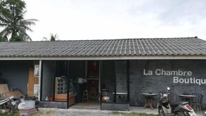 Un hôtel de charme doté d’un toit en tuiles, d’une entrée bien visible et d’un espace extérieur aménagé pour s’asseoir.