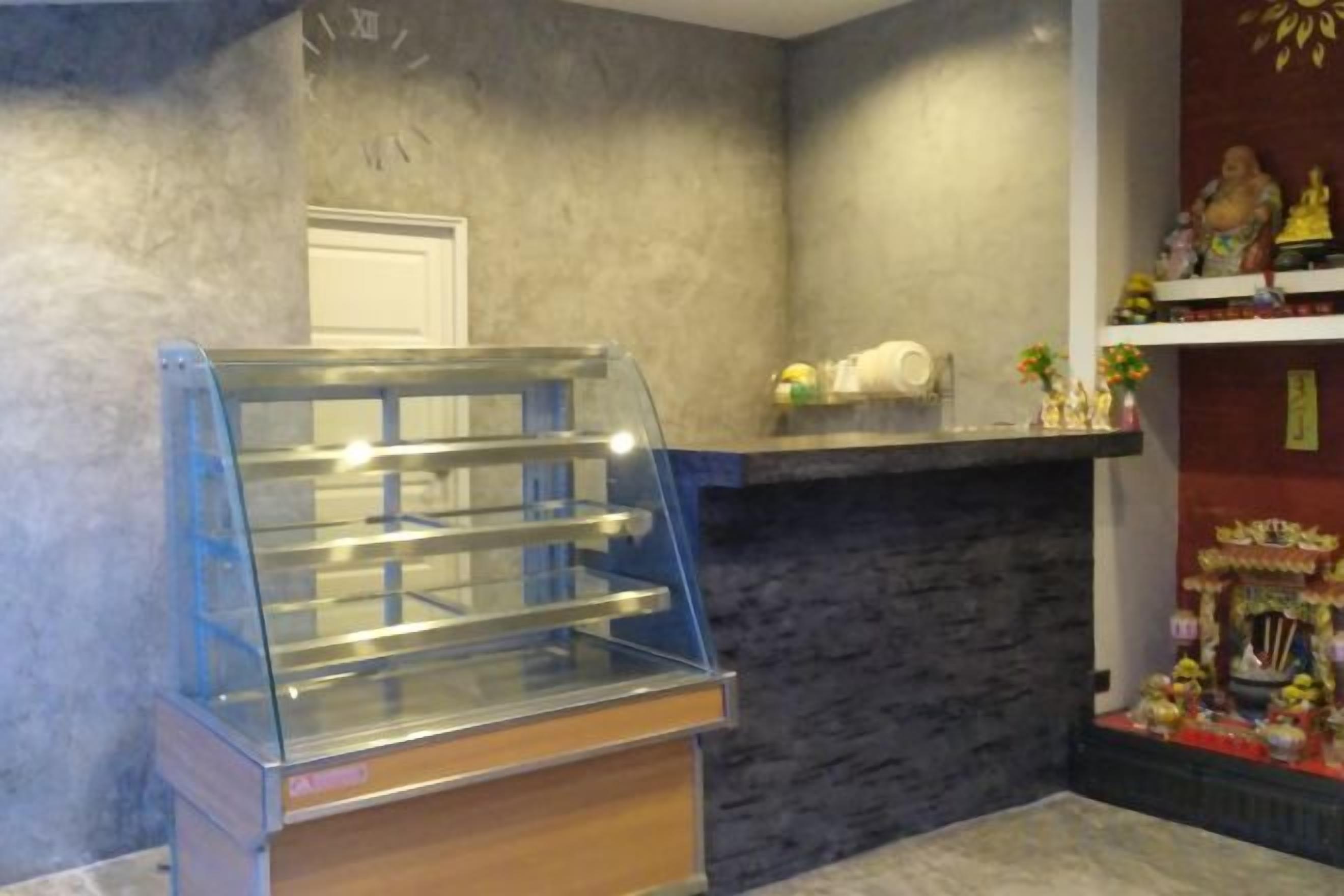 Vitrina de pastelería en el vestíbulo de un hotel, con una pared de piedra y una repisa decorativa con figuritas.
