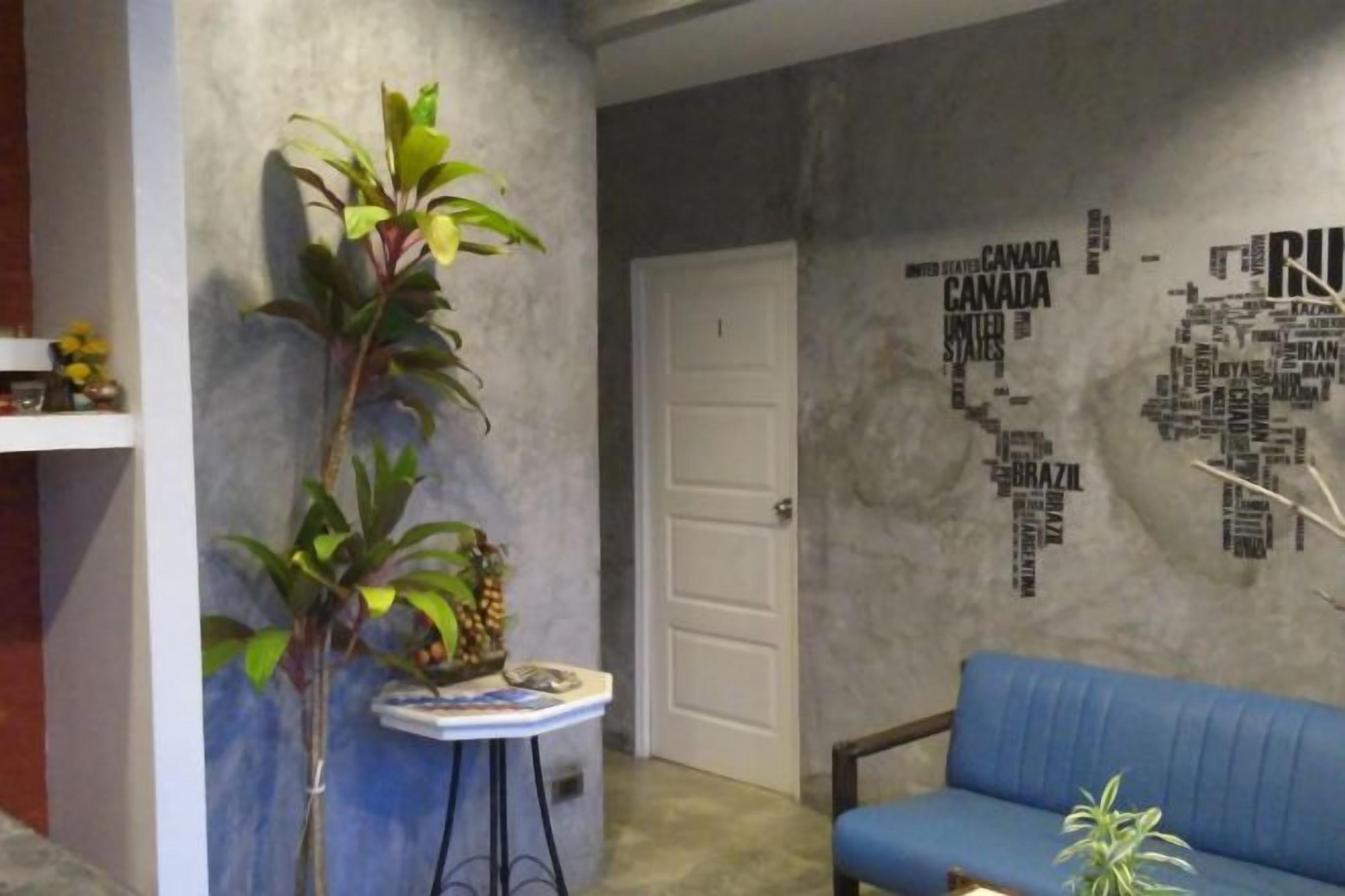 Una habitación con un sofá azul, una mesita con una planta y una pared con diseño de mapa del mundo.
