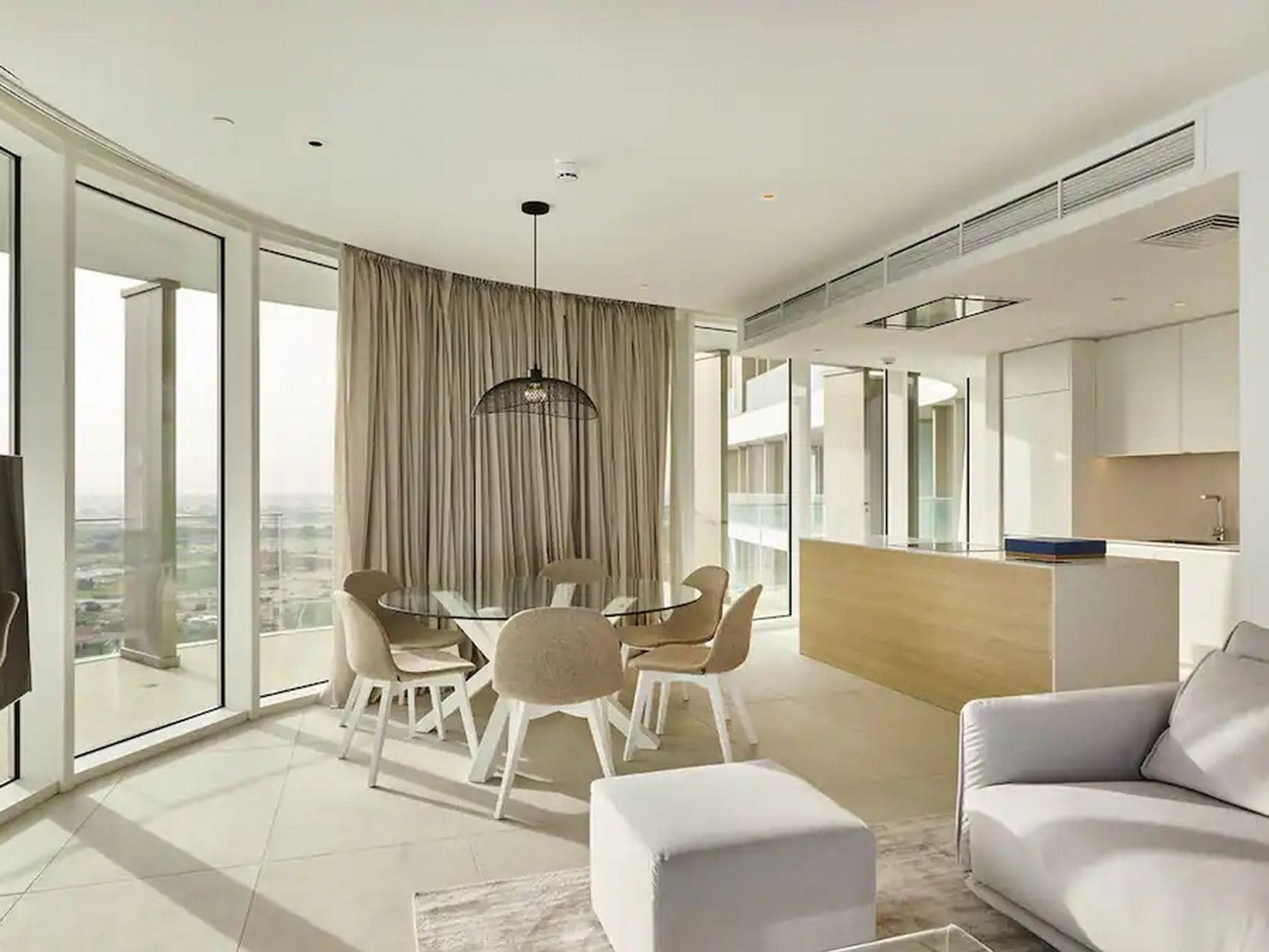 A modern living room with a dining area, a sofa, and a kitchen.