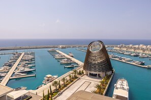 A marina with boats docked, a unique spiral building, and a clear view of the sea. - Ayia Napa Marina East Tower Suite (Ayia Napa)