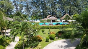 Ein Resort mit Swimmingpool, Palmen und strohgedeckten Gebäuden.