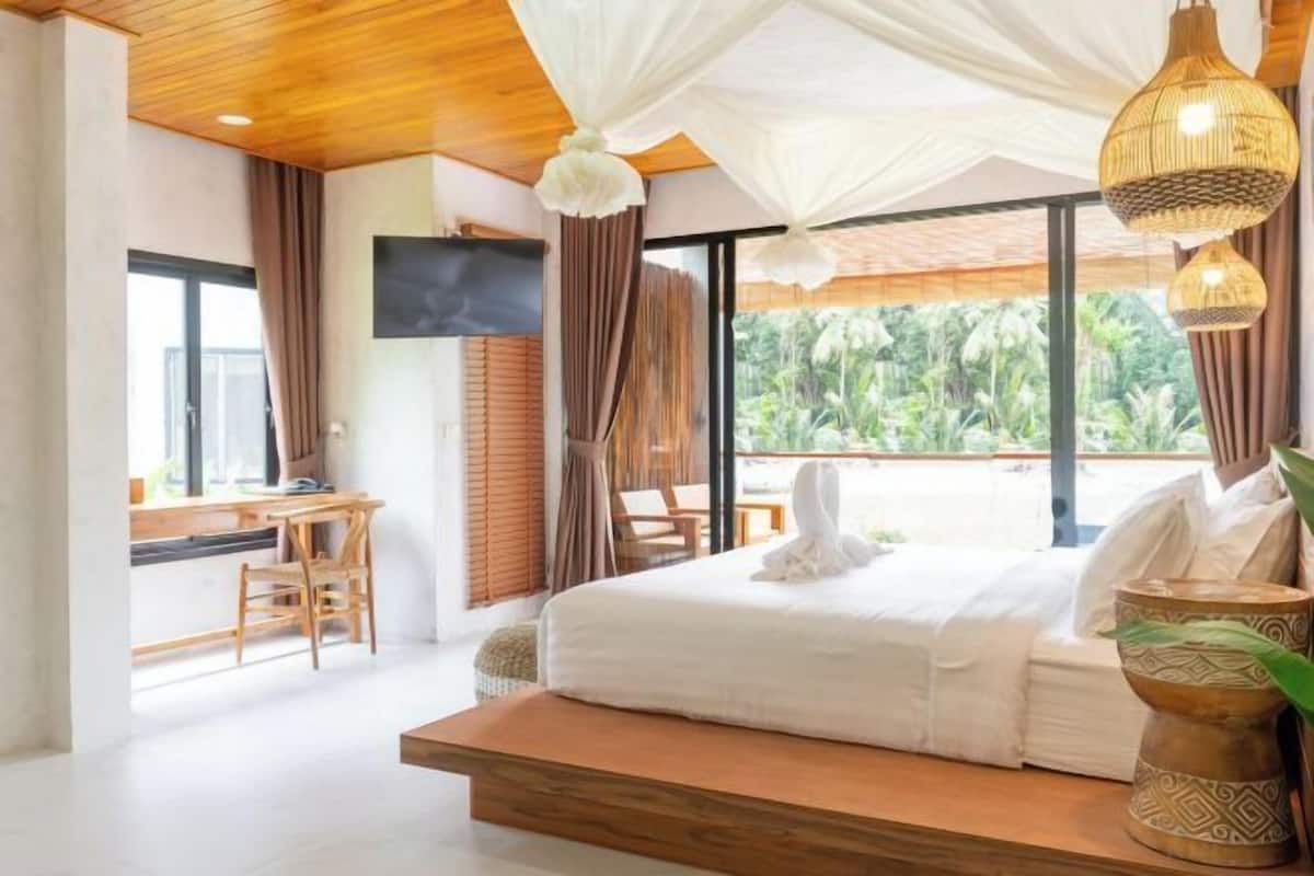 Une chambre avec un lit, un bureau et une vue sur la verdure.