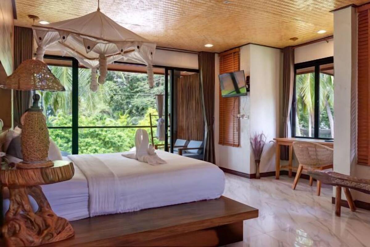 Une chambre avec un lit, une télévision, un bureau et une vue sur la verdure.