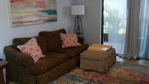 A living room with a brown sofa, patterned throw pillows, a wooden side table, a floor lamp, and a colorful rug. - Charming 3-bedroom house in wonderful Melbourne with WiFi, AC (Melbourne)