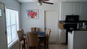 A compact kitchen with a dining area, a ceiling fan, a microwave, and a coffee maker. - Charming 3-bedroom house in wonderful Melbourne with WiFi, AC (Melbourne)