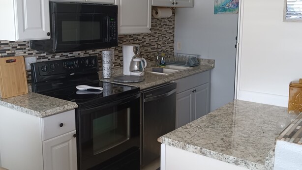 A kitchen with white cabinets, a black microwave, a coffee maker, and a dishwasher. - Charming 3-bedroom house in wonderful Melbourne with WiFi, AC (Melbourne)