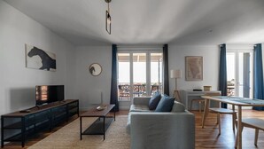 Una sala de estar moderna con sofá, mesa de centro, televisor y un comedor con mesa y sillas.