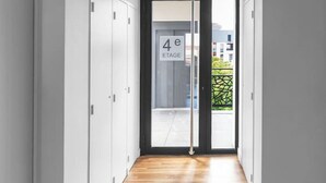 Un pasillo con suelo de madera, paredes blancas y una puerta con la inscripción '4e ETAGE'.