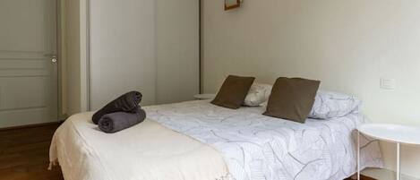Une chambre à coucher avec un lit, une table de chevet, une chaise, une armoire et une porte.