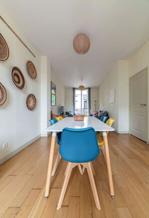 Comedor con una mesa blanca, sillas azules y suelo de madera.