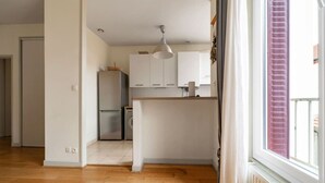 A kitchen with white cabinets, a stainless steel refrigerator, and a hanging pendant light. - 2-bedroom designer apartment, Thermes district (Vichy)