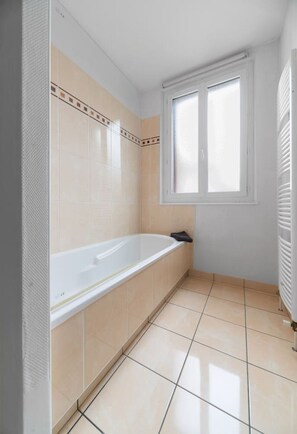 Un bagno con una vasca, una finestra e pavimento piastrellato.