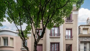 A multi-story residential building with a central entrance, balconies, and a tree in front. - 2-bedroom designer apartment, Thermes district (Vichy)