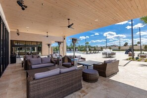 An outdoor patio area with wicker furniture, a pool, and a clear view of the sky.