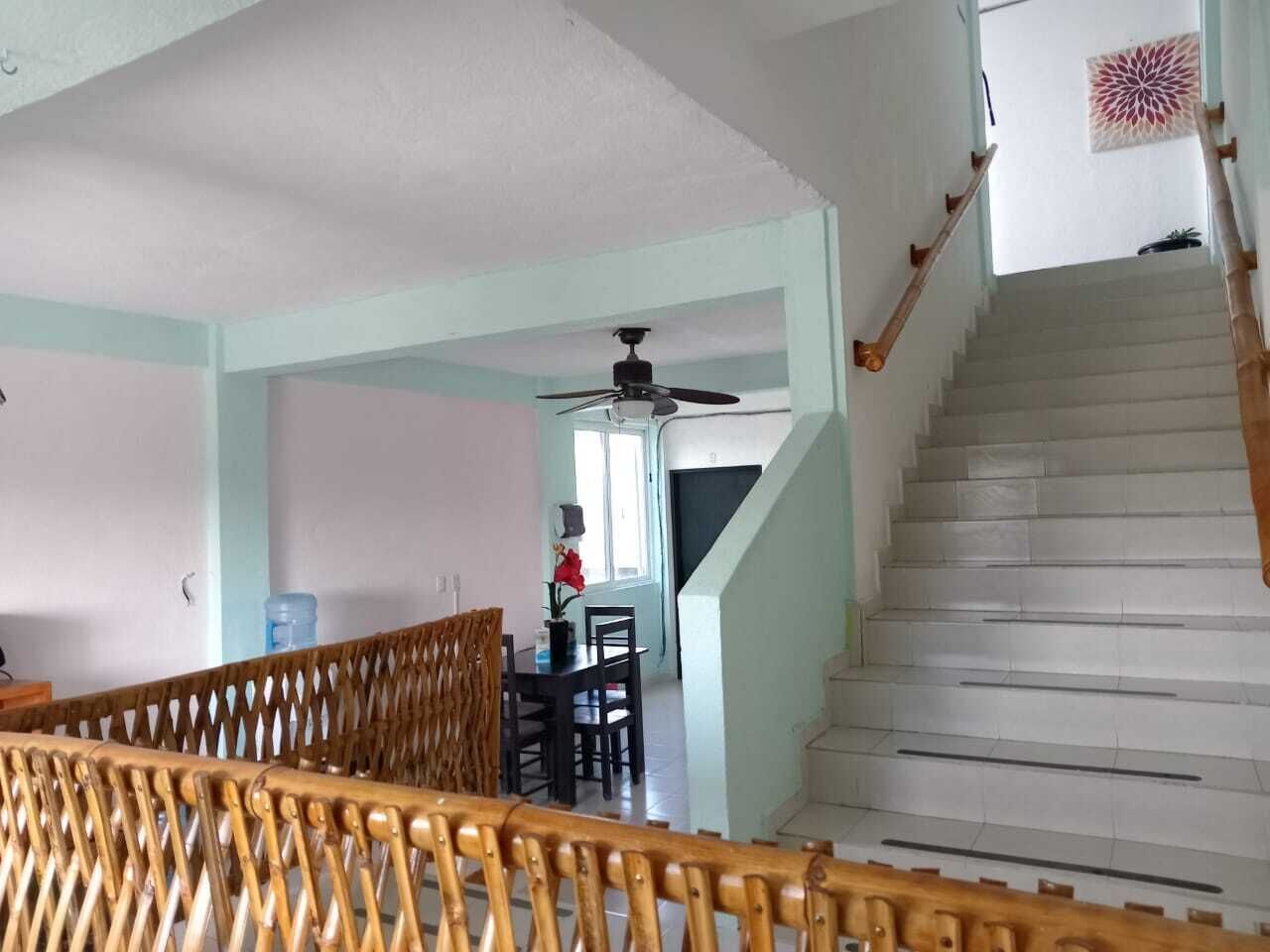 A staircase leading to a second floor, a dining area with a table and chairs, and a ceiling fan.