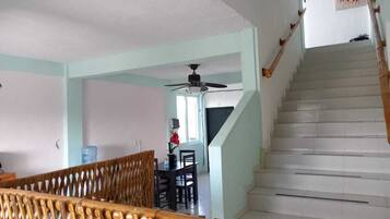 A staircase leading to a second floor, a dining area with a table and chairs, and a ceiling fan.